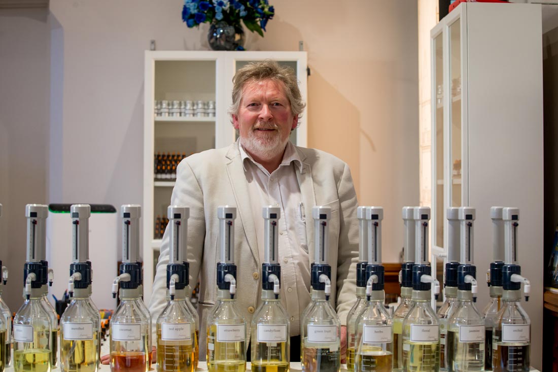 A person smelling different perfume ingredients in a laboratory setting