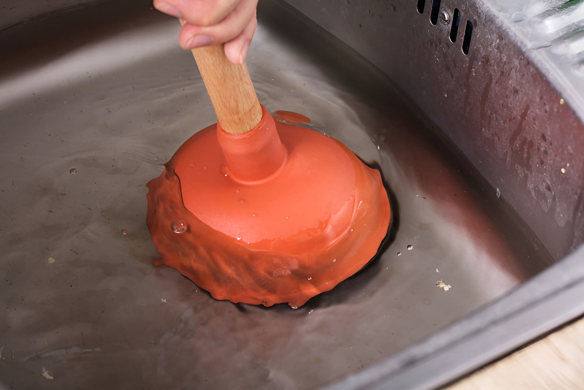 A Person is Using a Plunger to Unblock a Sink — Simpson's Plumbing & Maintenance Service in Dakabin, QLD