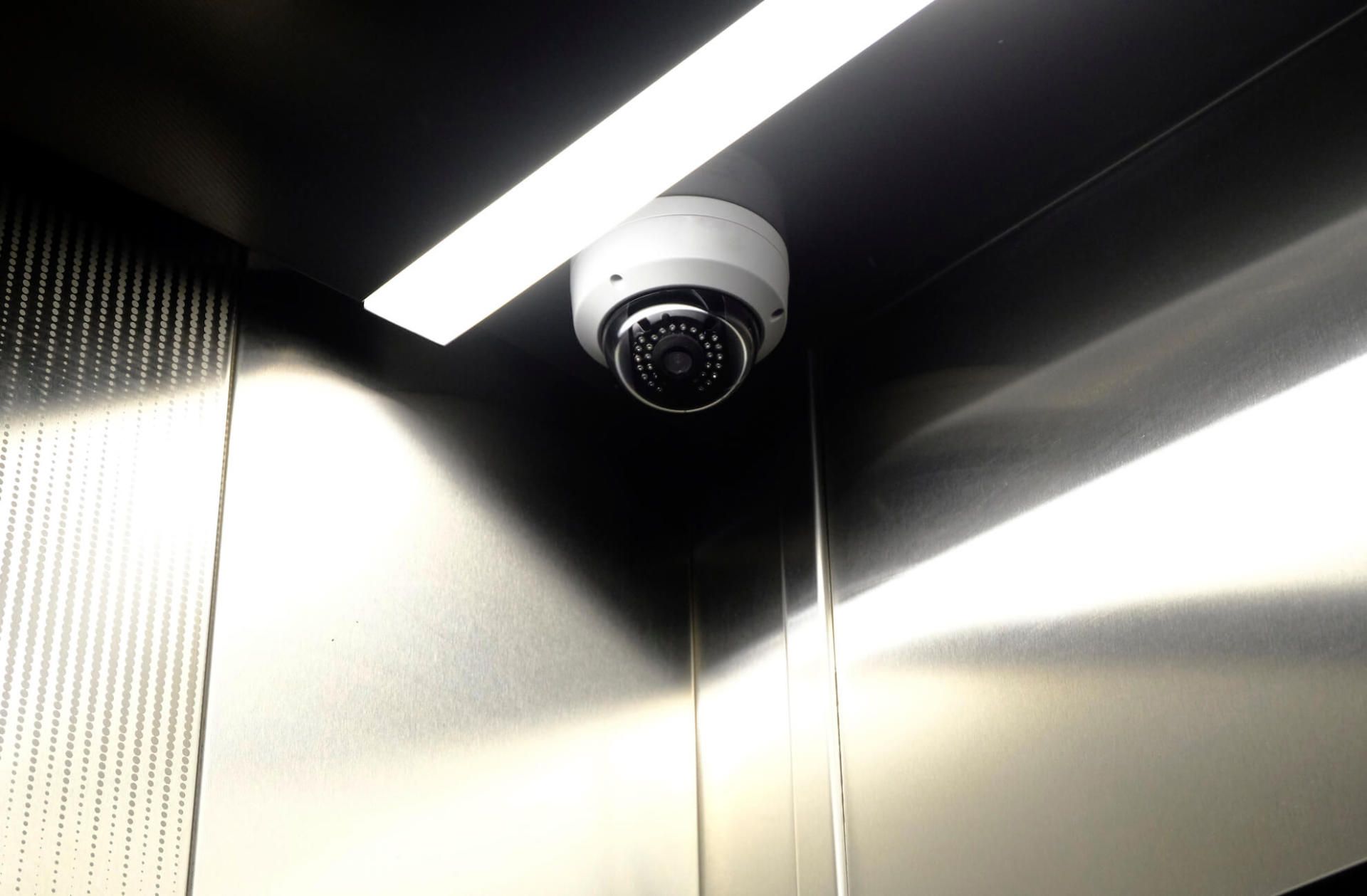 A security camera is hanging from the ceiling of an elevator