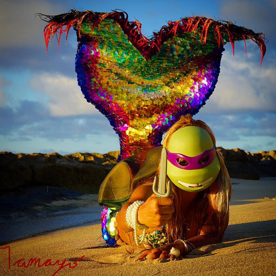 A woman in a mermaid costume is giving a thumbs up