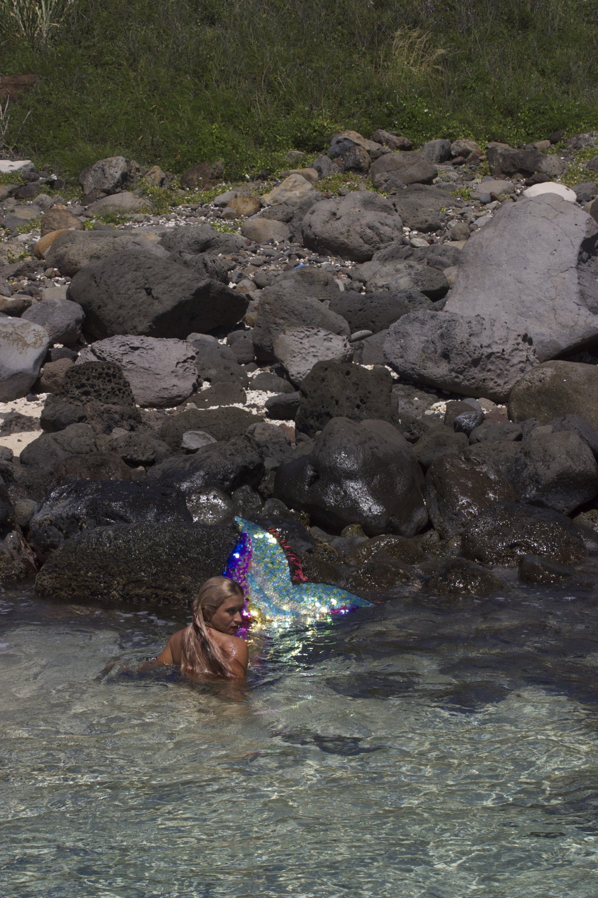 A woman in a mermaid costume is swimming in the ocean.