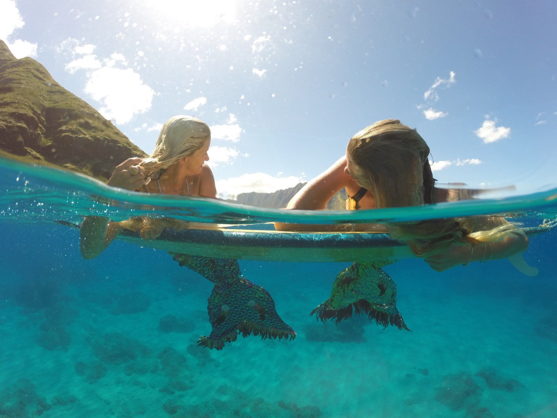 A couple of mermaids are swimming in the ocean.