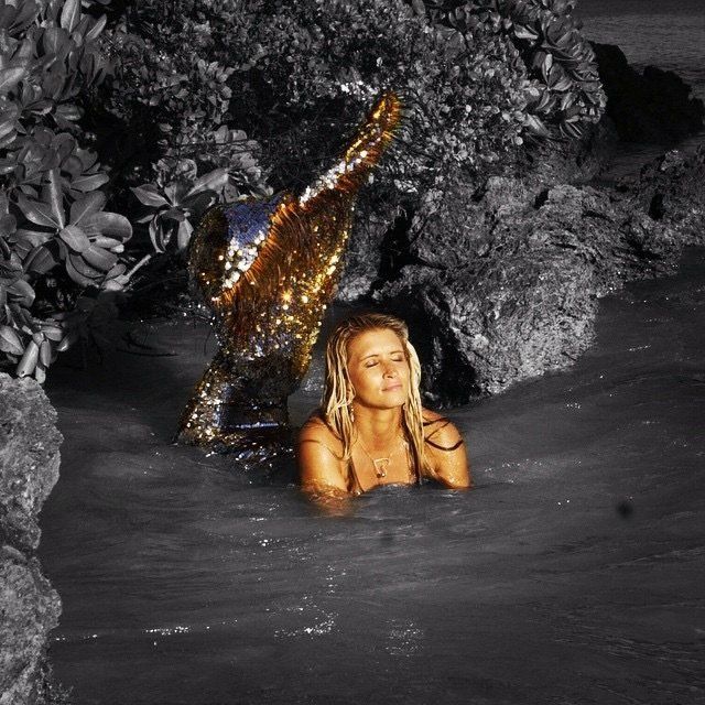 A woman in a mermaid costume is swimming in the water