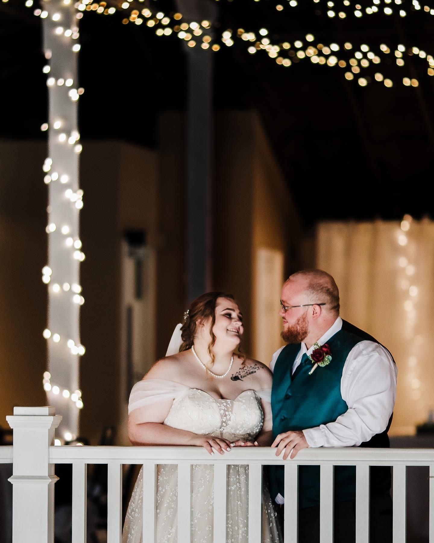 a bride and groom are standing on a balcony looking at each other .