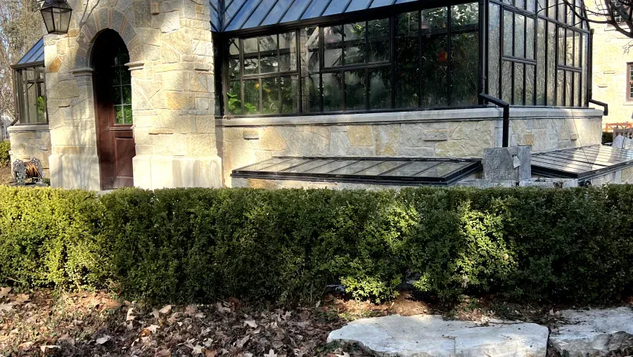 There is a greenhouse in the backyard of a house.