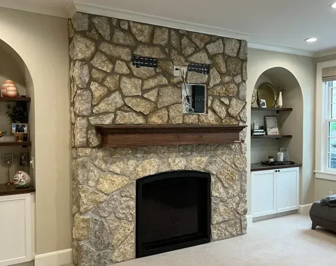 A living room with a fireplace and a stone wall