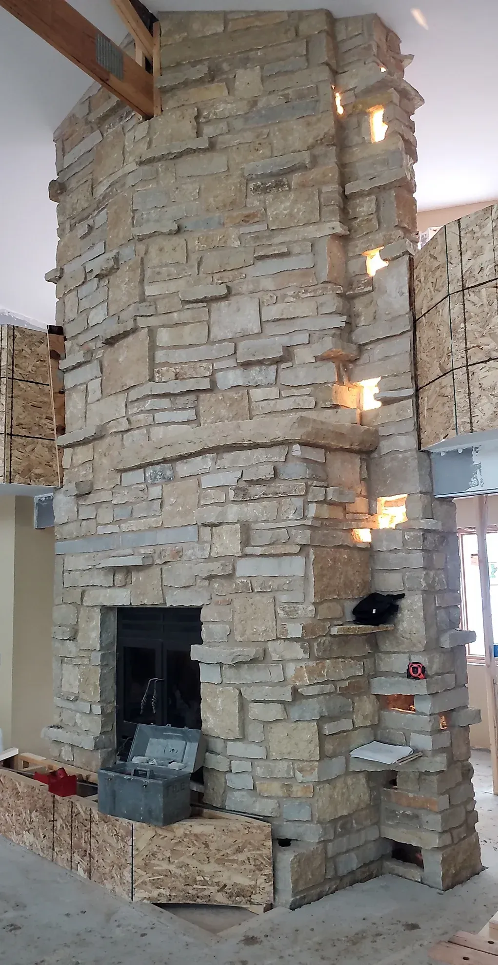 There is a large stone fireplace in the middle of the room.