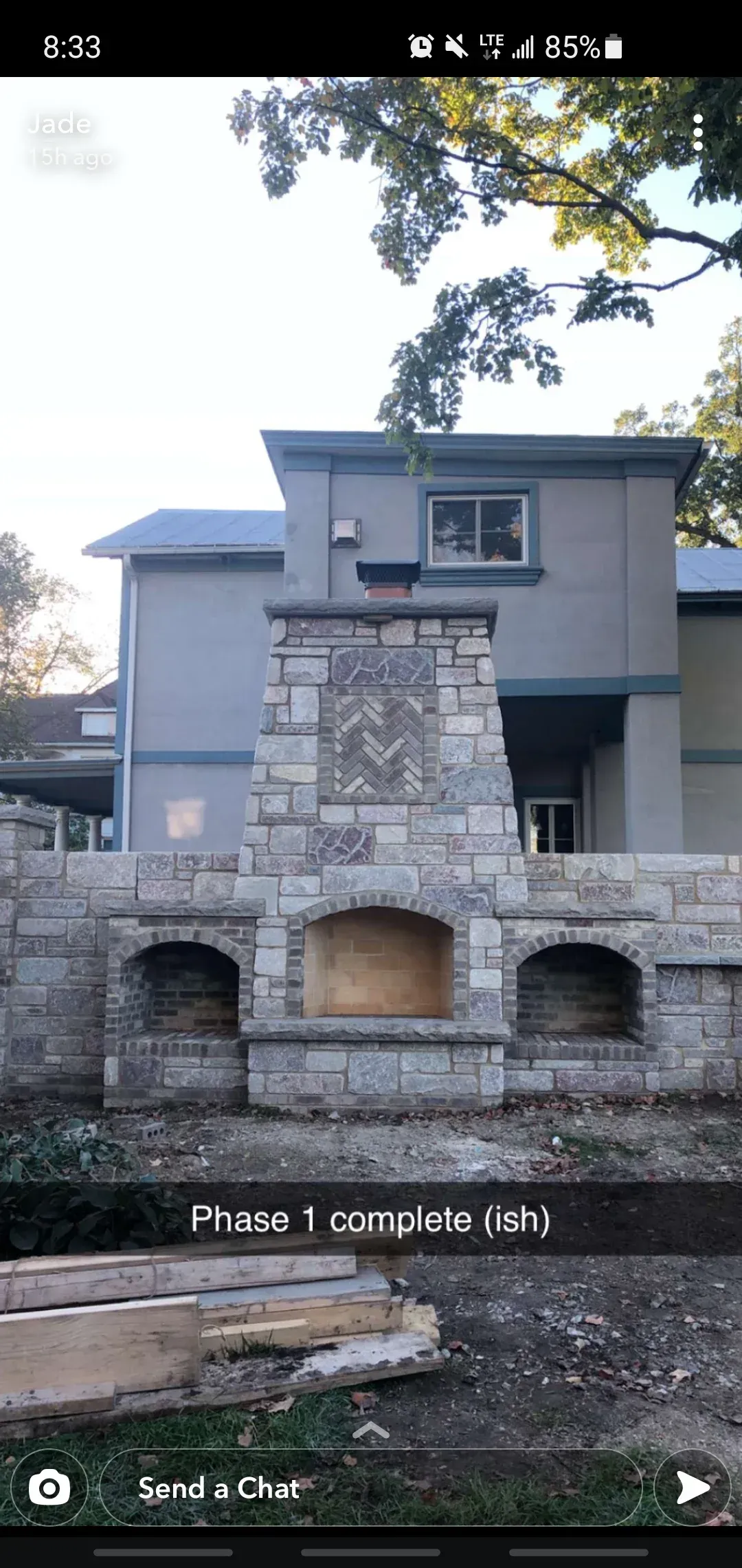 A stone fireplace is being built in front of a house.