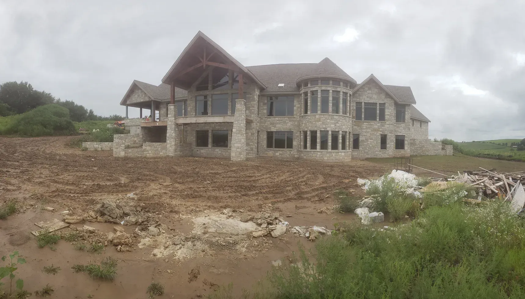 A large stone house is sitting in the middle of a dirt field.