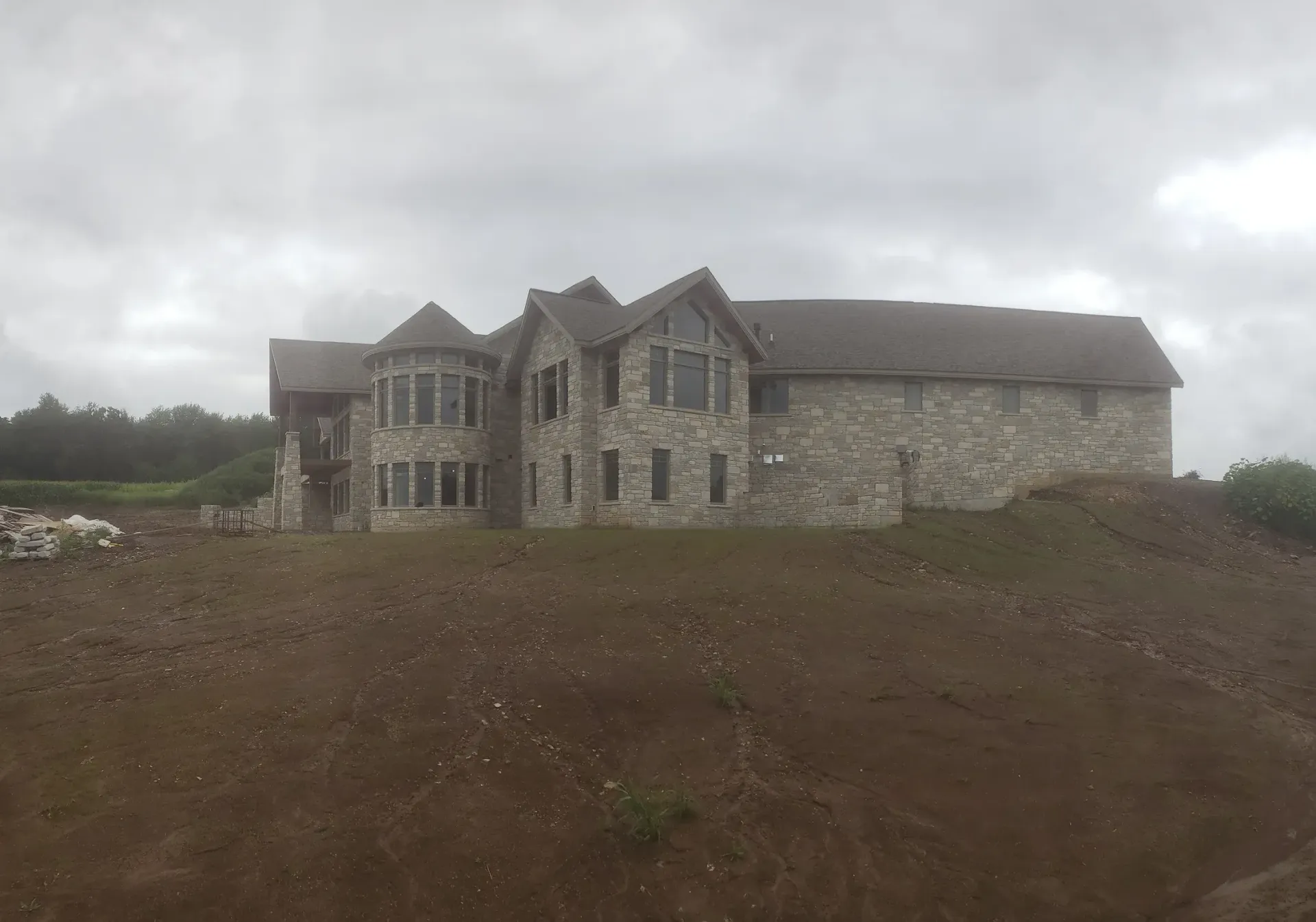 A large stone house is sitting on top of a dirt hill.