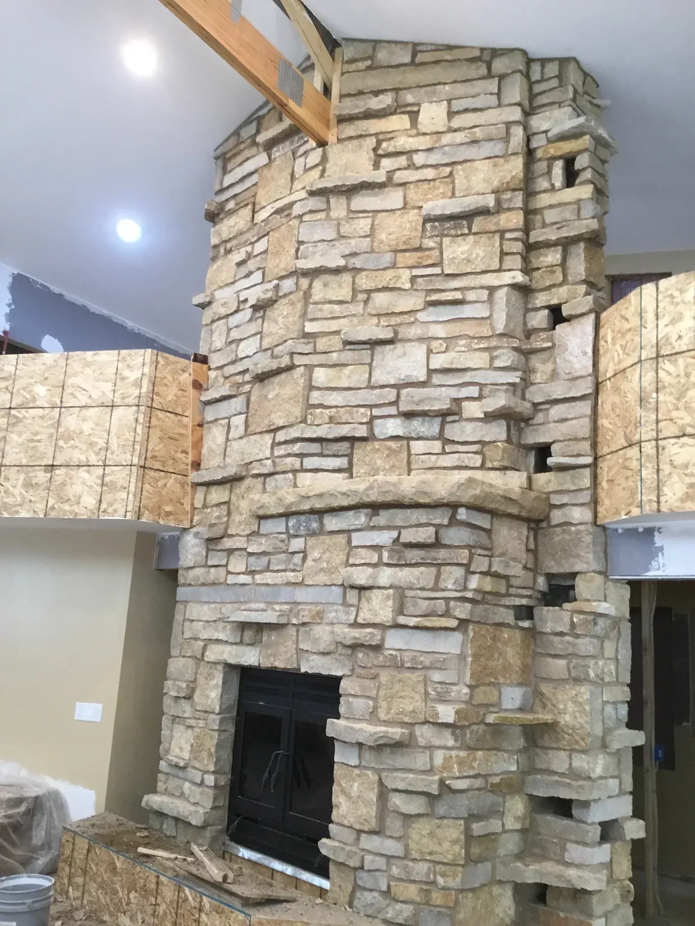 A large stone fireplace is being built in a living room.