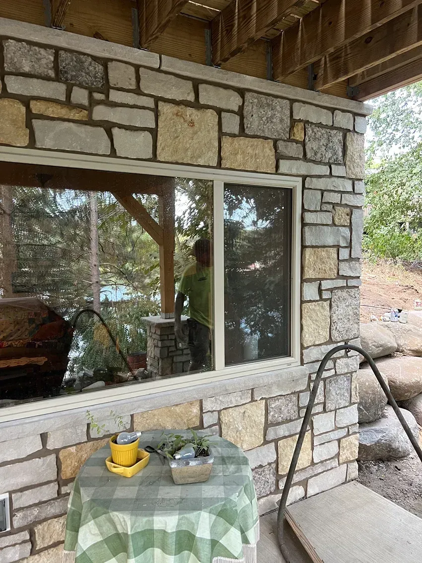 A stone wall with a window and a table in front of it.
