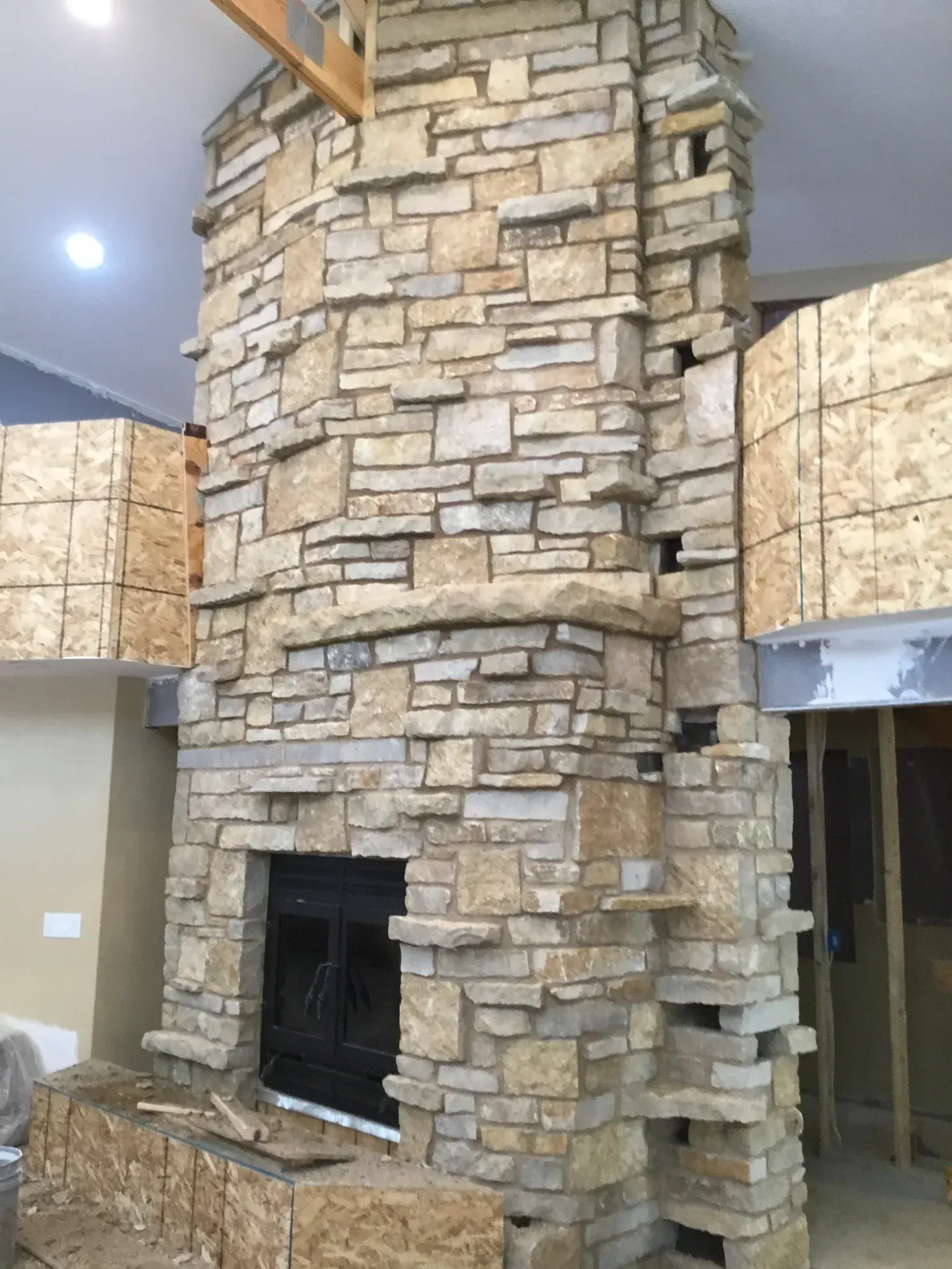 A large stone fireplace is being built in a living room.