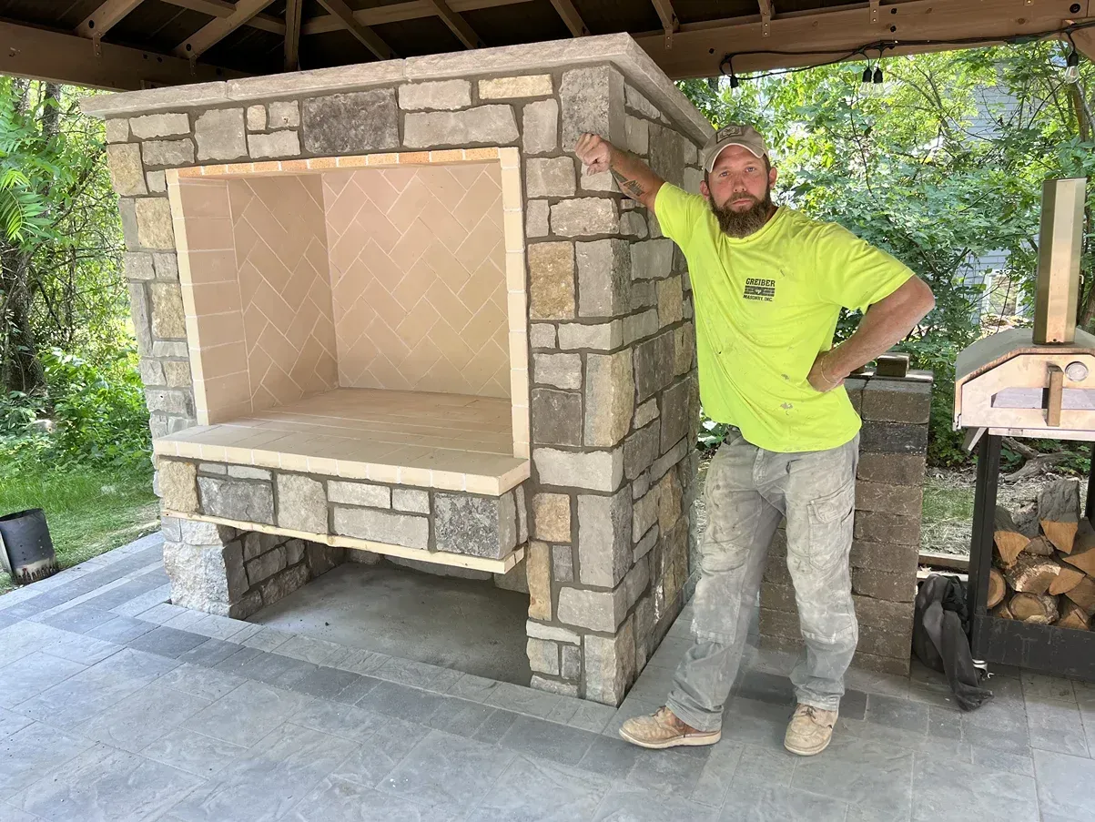 A man in a neon green shirt is standing next to a stone wall.