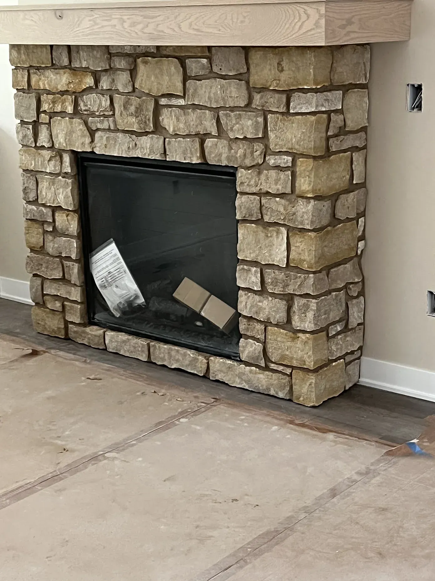 A stone fireplace is being built in a living room.