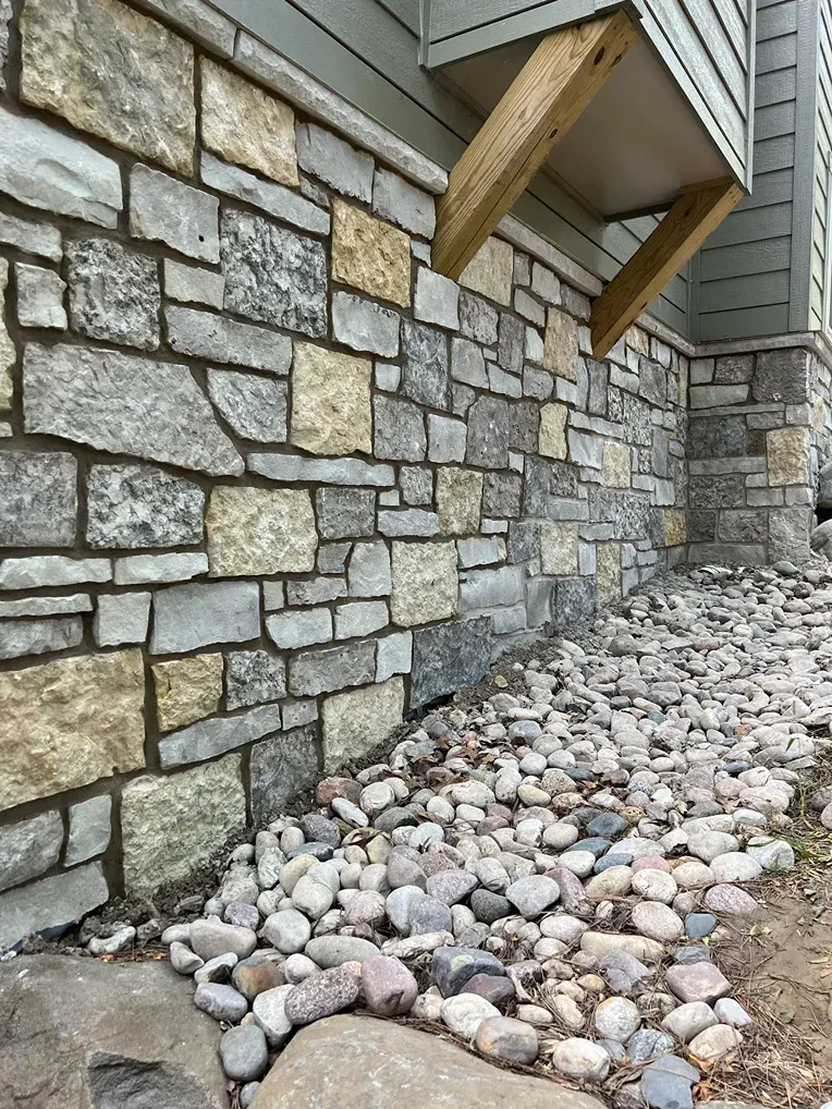 A stone wall with a lot of rocks in front of it.