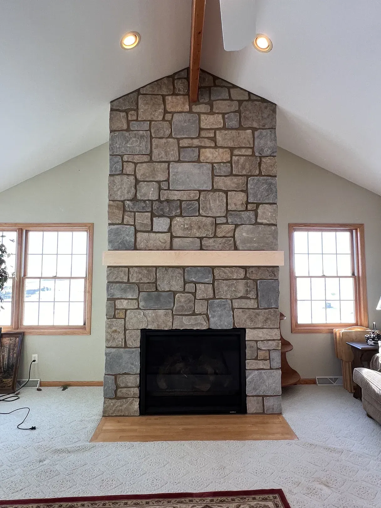 A stone fireplace in a living room with a vaulted ceiling