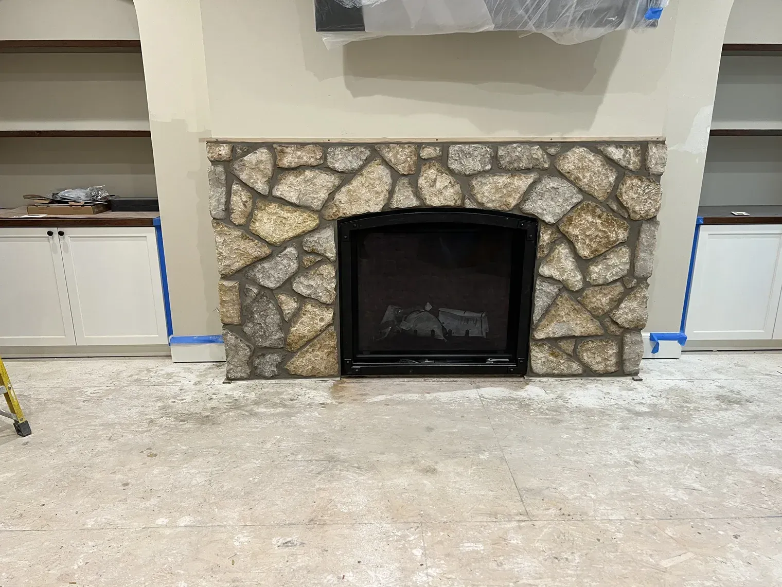 A fireplace in a living room with a stone fireplace surround.