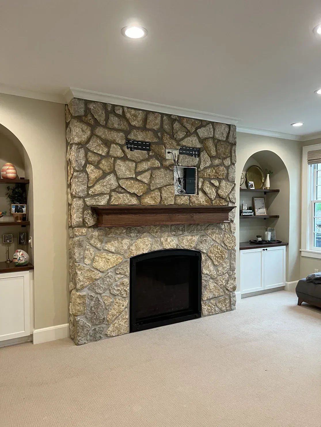 A living room with a stone fireplace and a flat screen tv.