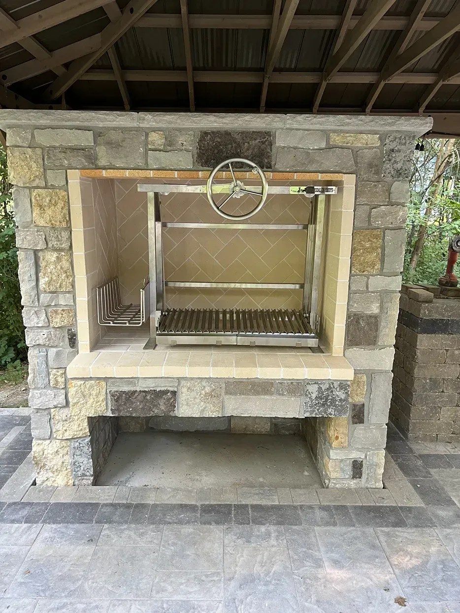 A stone fireplace with a grill inside of it.