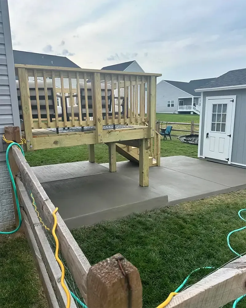 wooden deck and stairs leading to brushed concrete patio