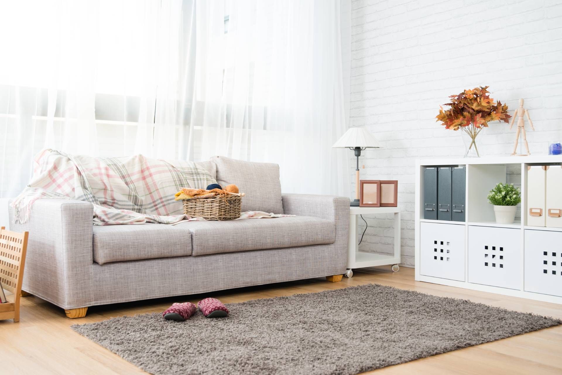 Living room with a gray couch, rug, and white shelves with decorations.
