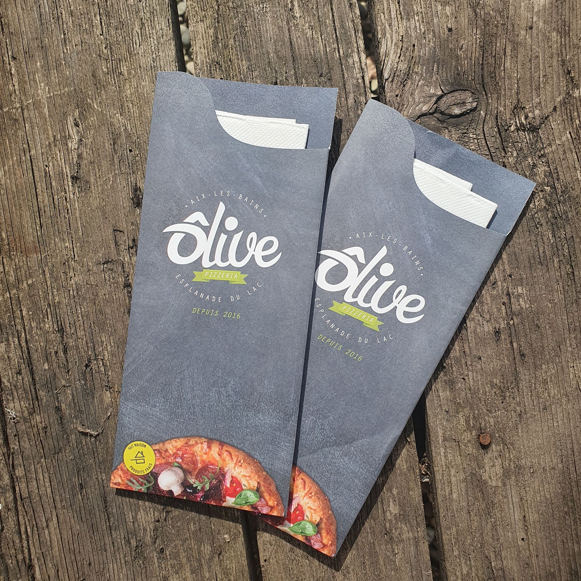 Deux sachets alimentaires gris sur une surface en bois avec le logo « Olive » et un graphique de pizza.