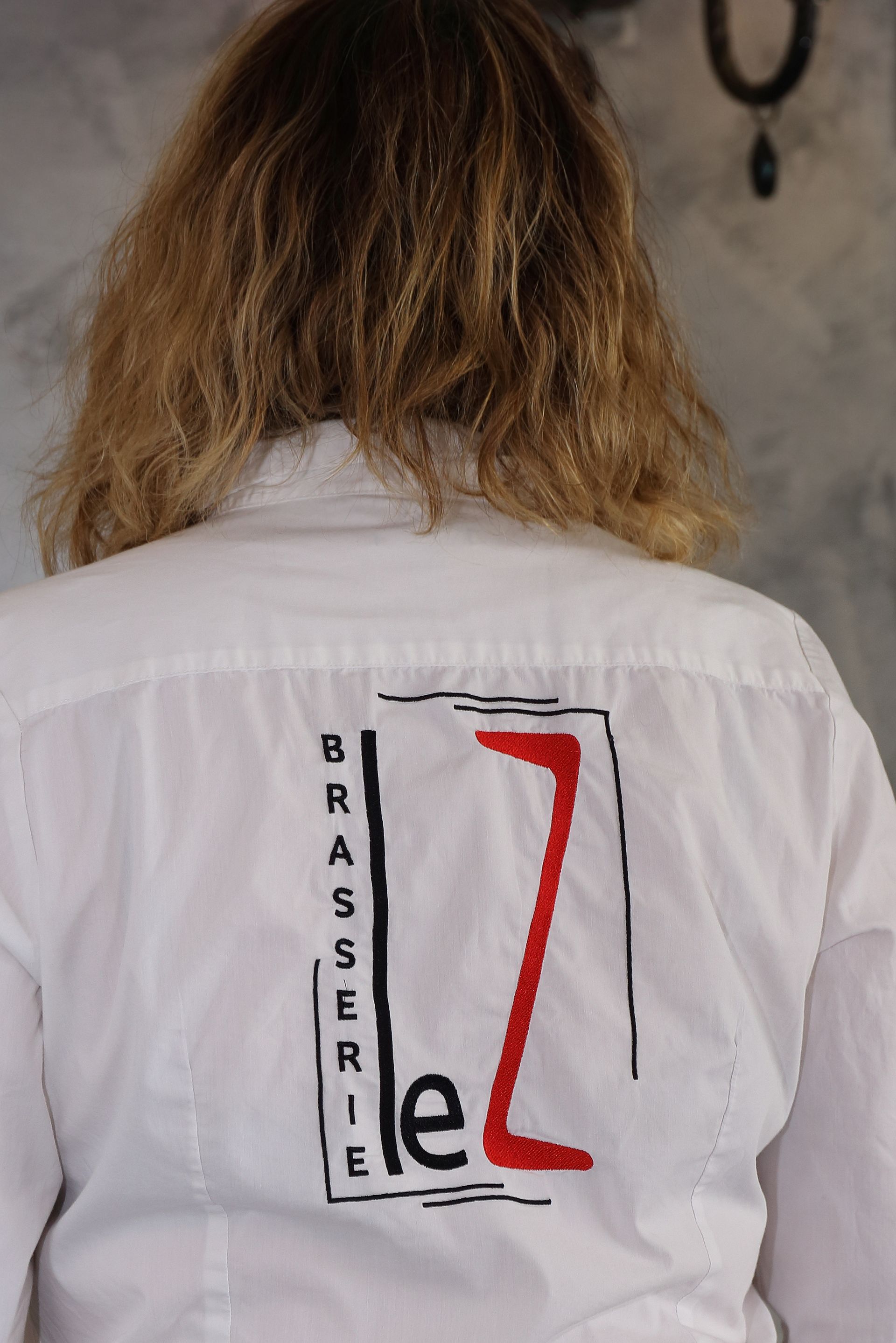 Femme portant une chemise blanche avec un logo rouge et noir 