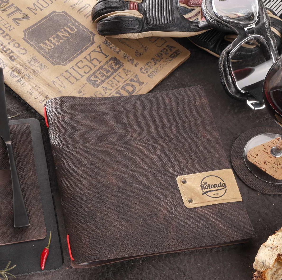 Menu et autres éléments sur une table, y compris un menu relié en cuir, des piments rouges et un menu sur le thème du whisky.