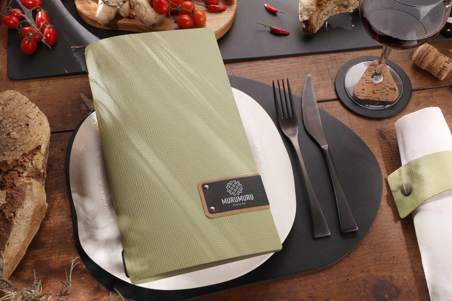 Menu vert sur une assiette blanche avec des couverts, du pain, du vin et d'autres aliments sur une table en bois.