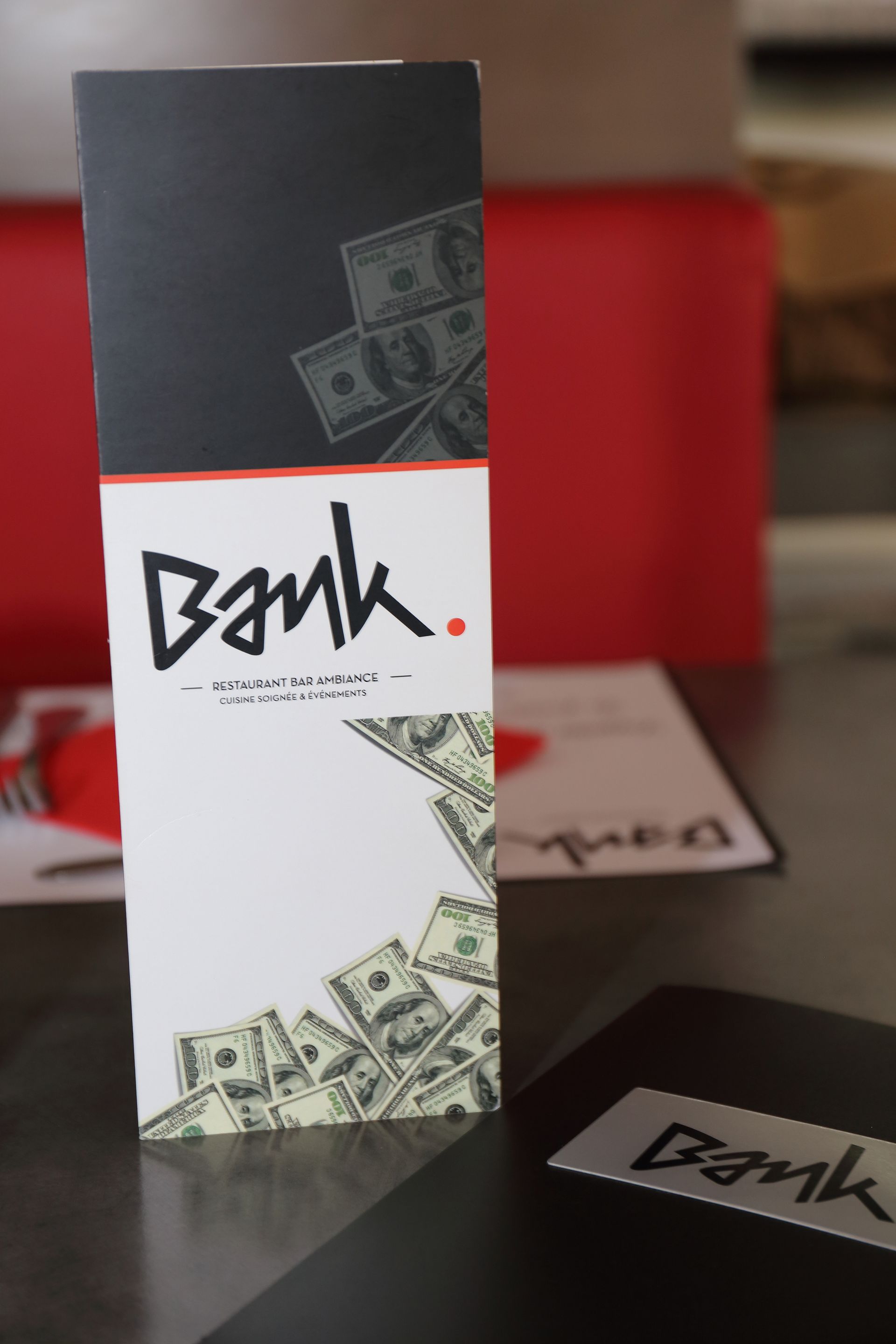 Menu du restaurant « Bank » avec un motif de billet de banque. Noir et blanc avec des touches de rouge.
