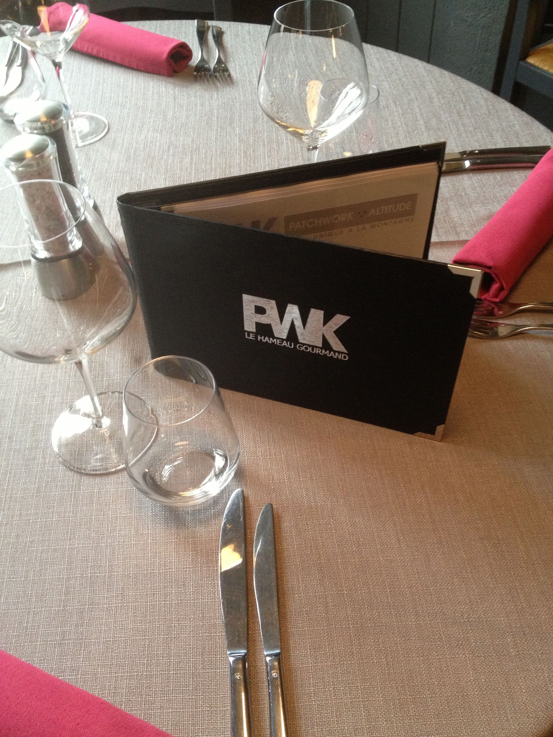 Décoration de table avec menu, verres à vin, couverts et serviettes roses.