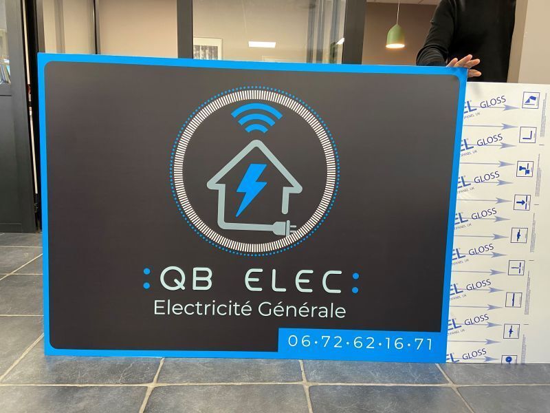 Panneau de QB Elec, entreprise de services électriques, avec une maison et un éclair en guise de logo. Couleurs : bleu et noir.