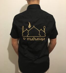 Personne portant une chemise noire avec une broderie dorée d'une mosquée et 
