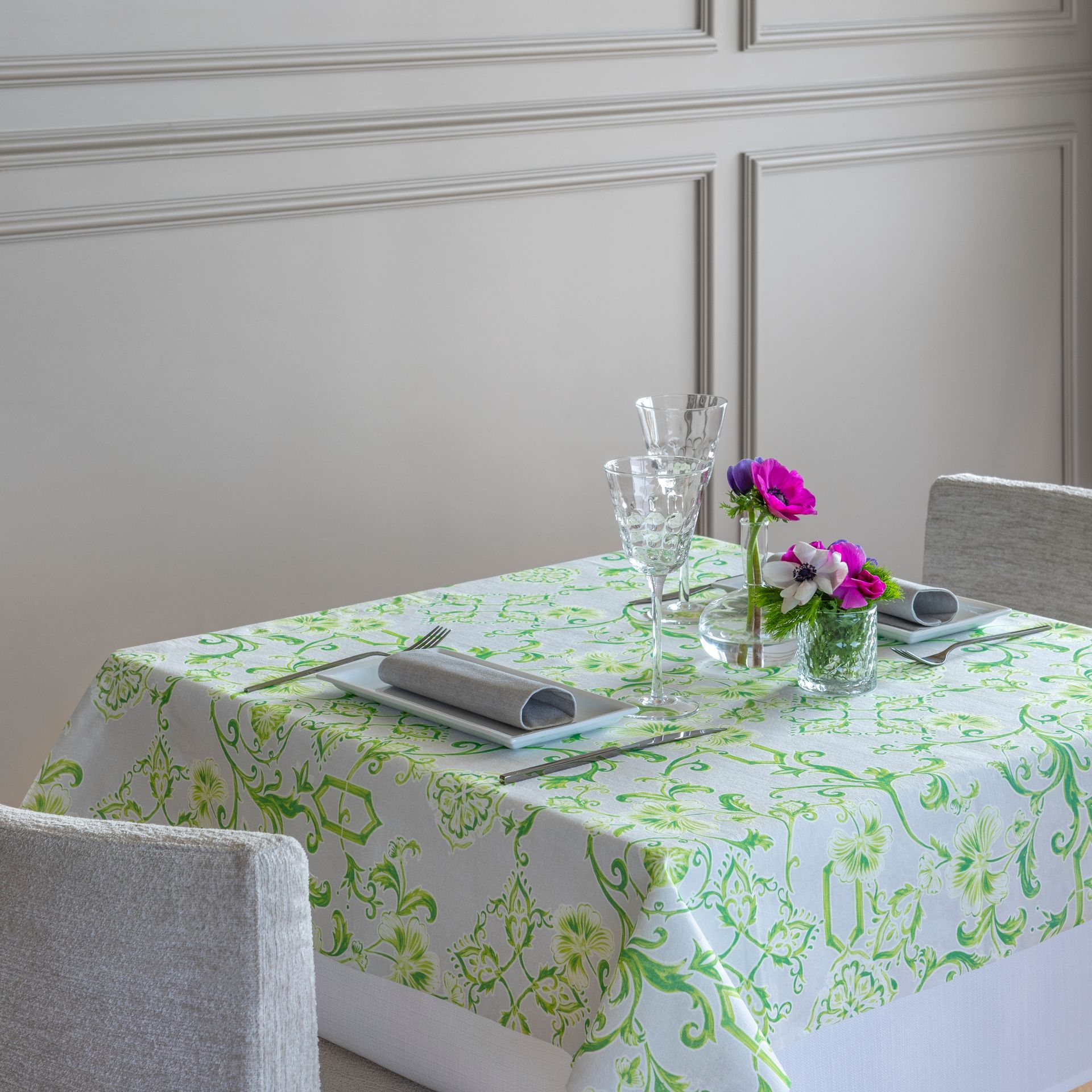 Set de table pour dîner avec nappe fleurie verte, verres et fleurs.