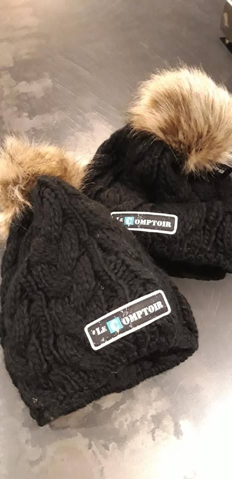 Deux bonnets d'hiver en tricot noir avec pompons en fourrure, chacun avec un logo indiquant 