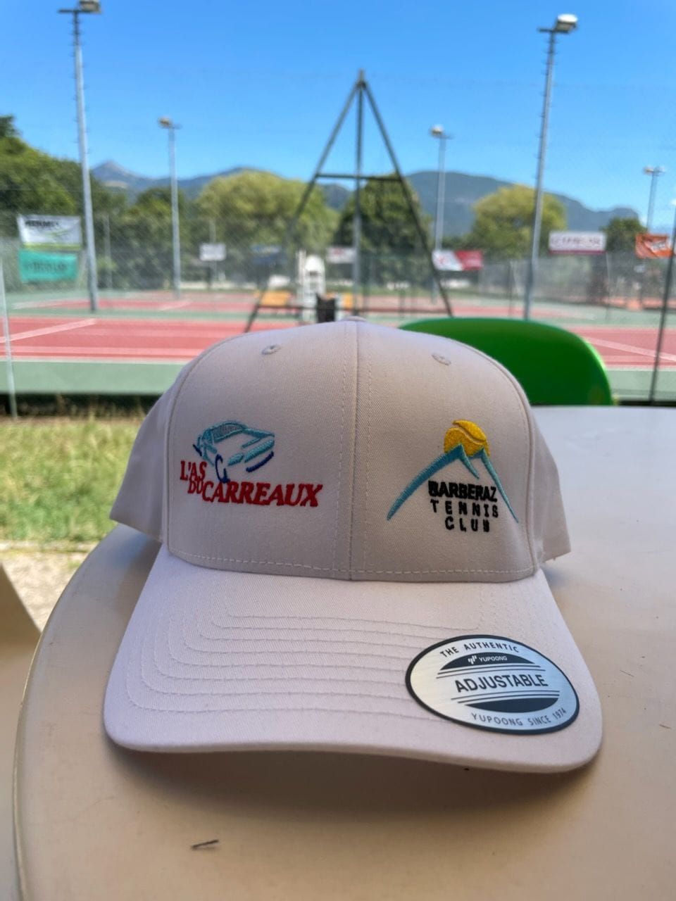 Casquette de baseball blanche avec des logos sur une table dans un club de tennis.