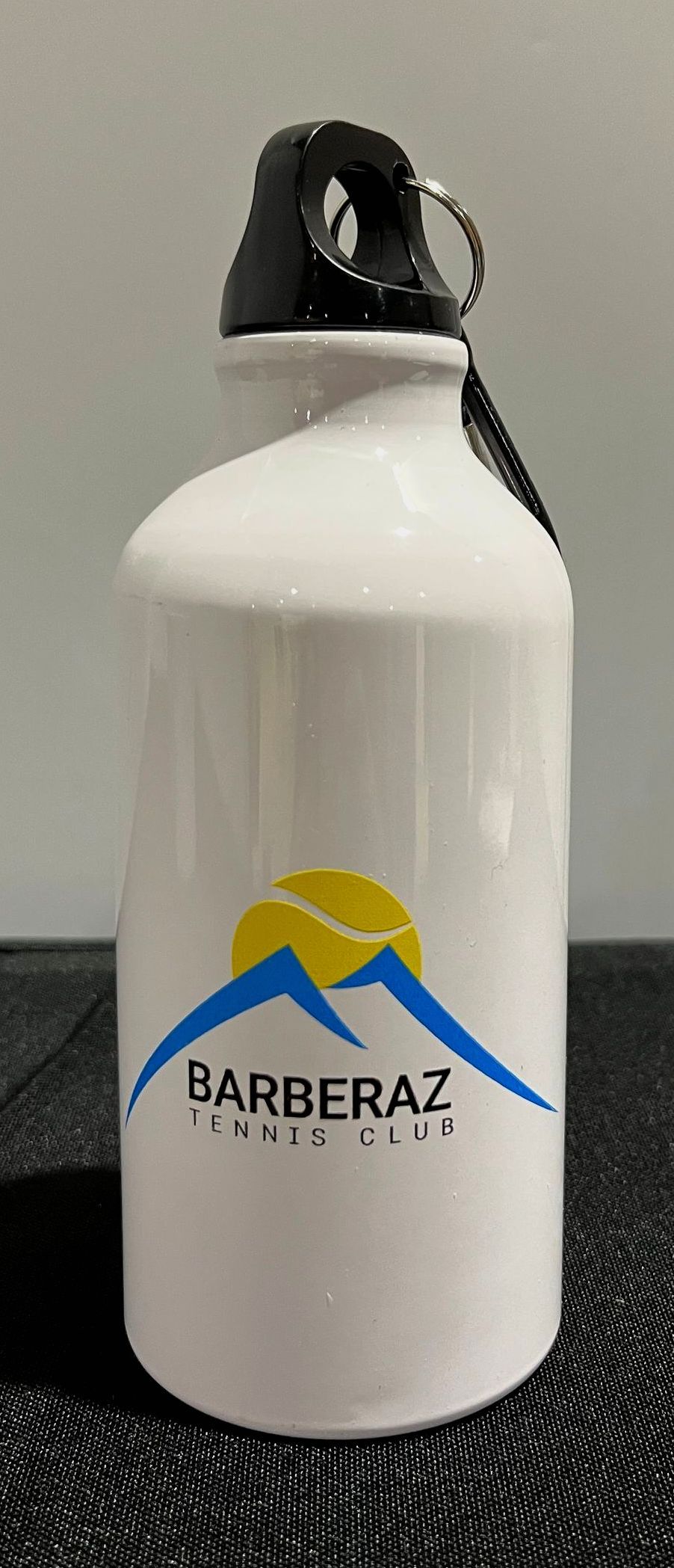 Gourde blanche avec bouchon, anneau et logo noirs : soleil jaune sur montagnes bleues. Texte : « BARBERAZ FITNESS CLUB ».