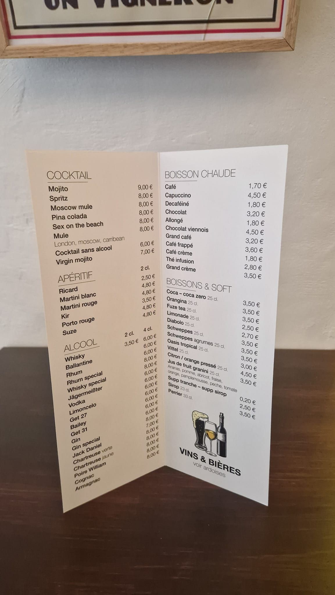Un menu à trois volets sur une table en bois répertorie les options de nourriture et de boissons.