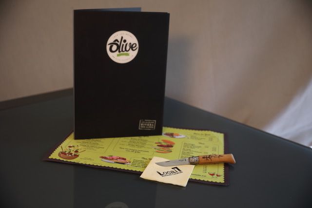 Menu Olives Noires sur une table avec un set de table et un couteau.
