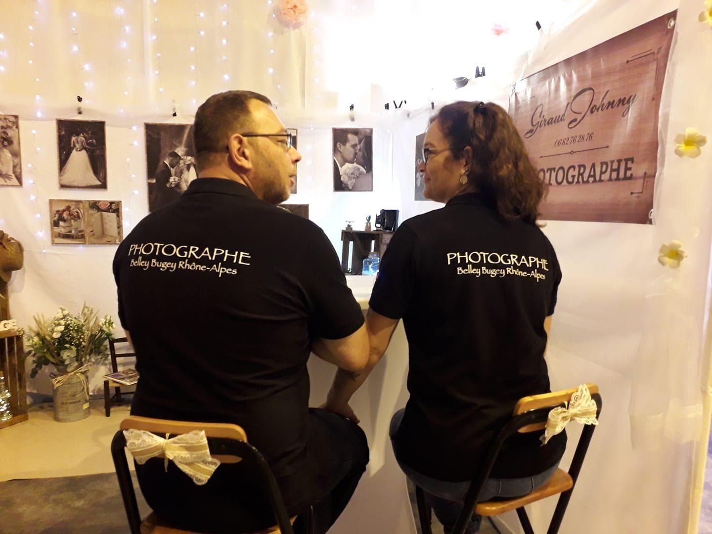 Deux personnes, portant des chemises noires assorties avec « Photographe » au dos, sont assises à un comptoir.