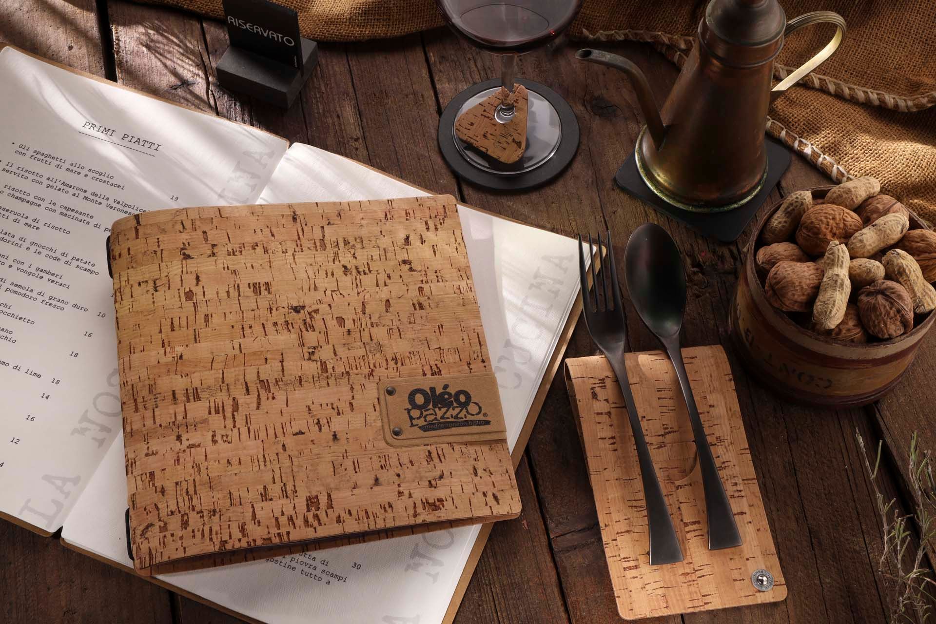 Table en bois avec menu en liège, couverts, cacahuètes et cafetière.
