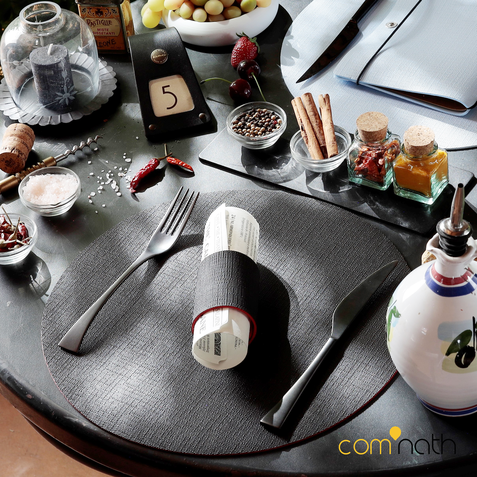 Décoration de table avec fourchette, couteau, rond de serviette, épices et distributeur d'huile d'olive.