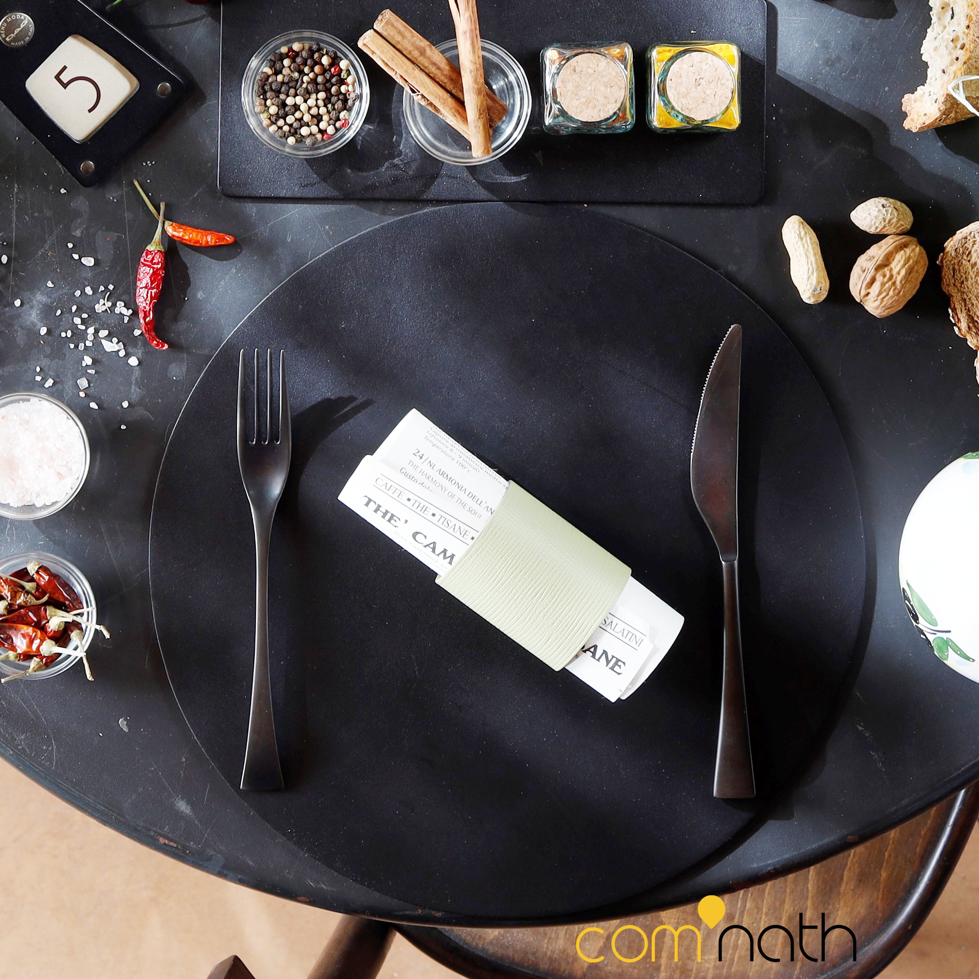 Décoration de table noire avec fourchette, couteau, serviette, épices et petits plats.