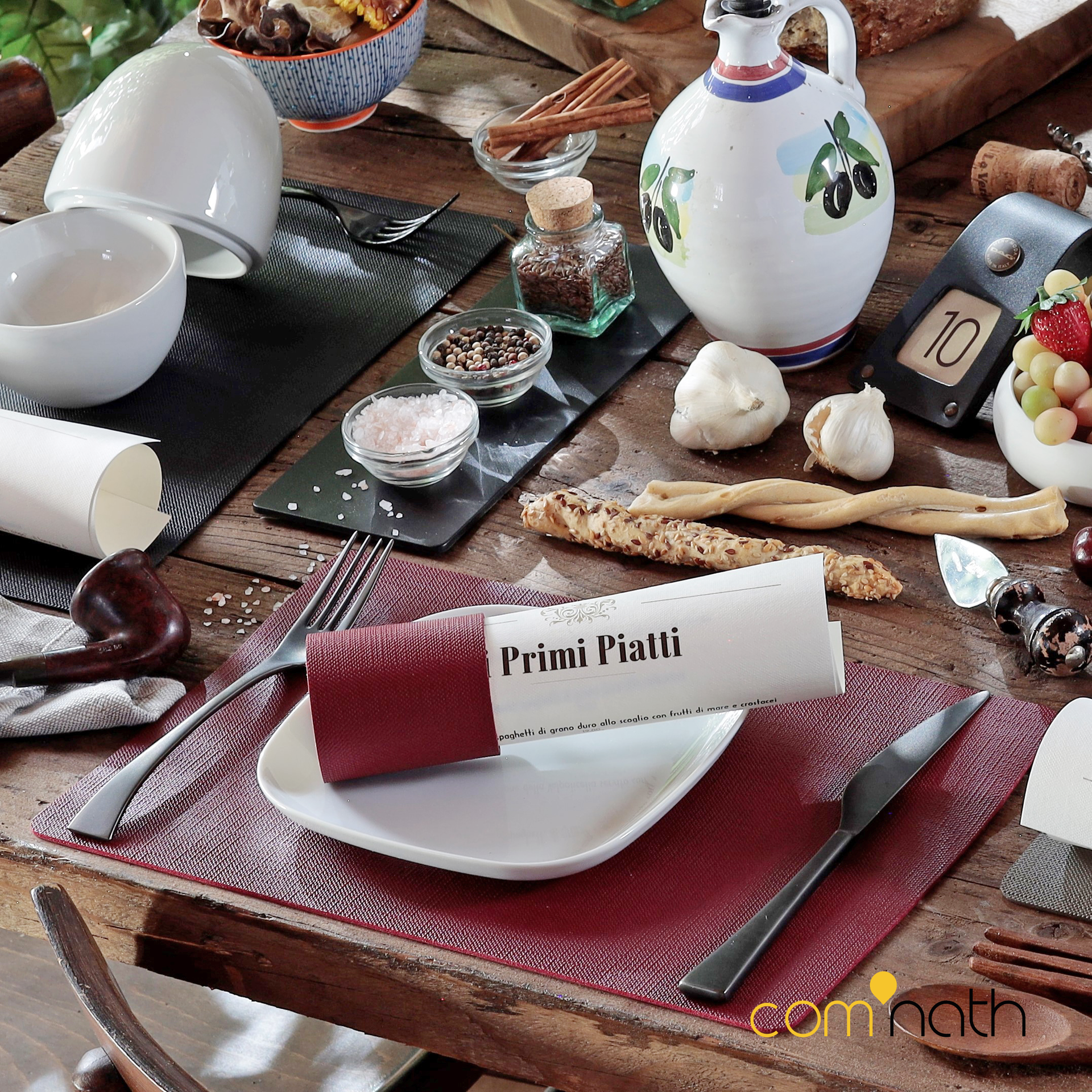 Gros plan d'une table rustique dressée pour un repas, avec des assiettes, des assaisonnements et un marque-place « Primi Piatti ».