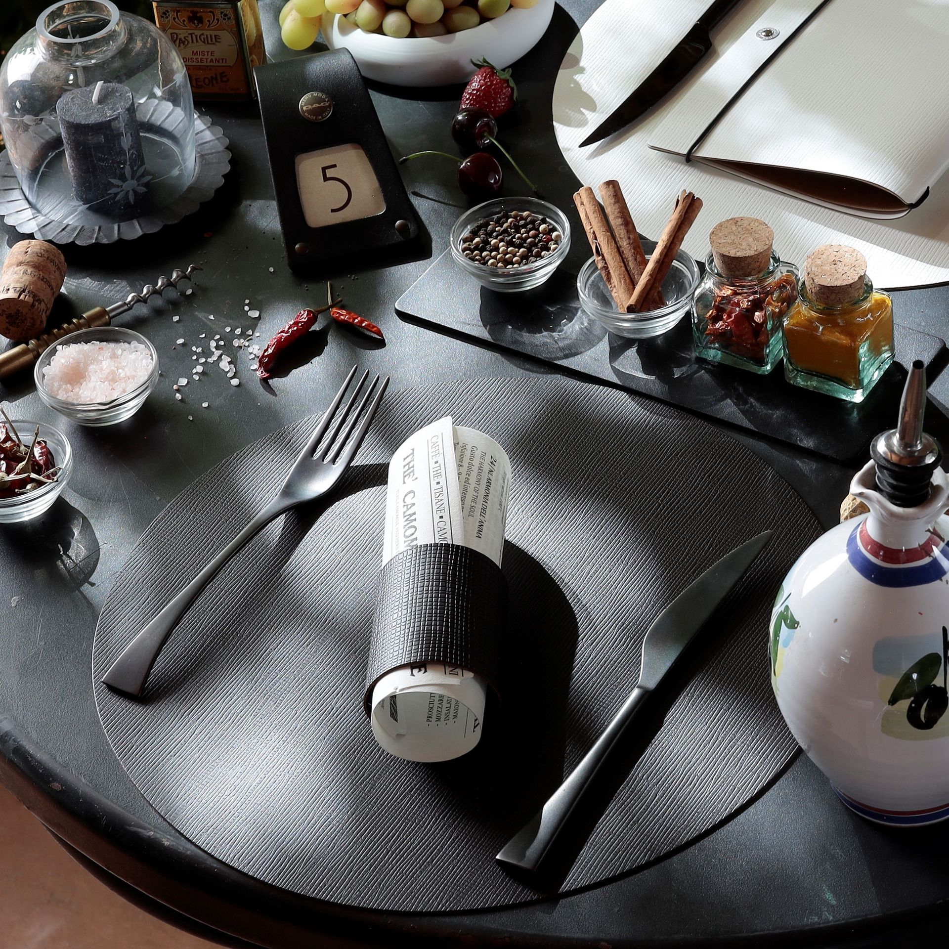 Table dressée pour dîner avec couverts, épices et huile d'olive.