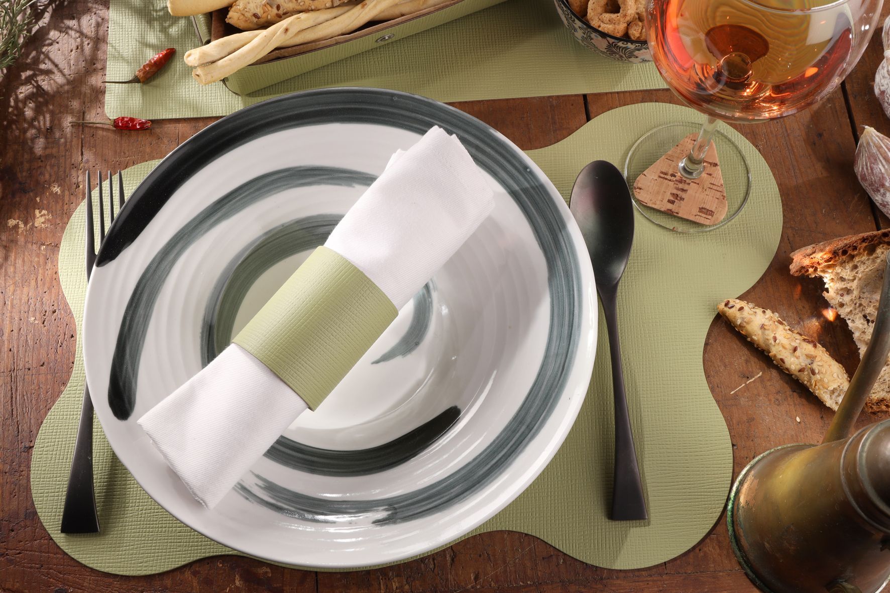 Couvert avec rond de serviette, assiette, couverts et nourriture sur une table en bois.