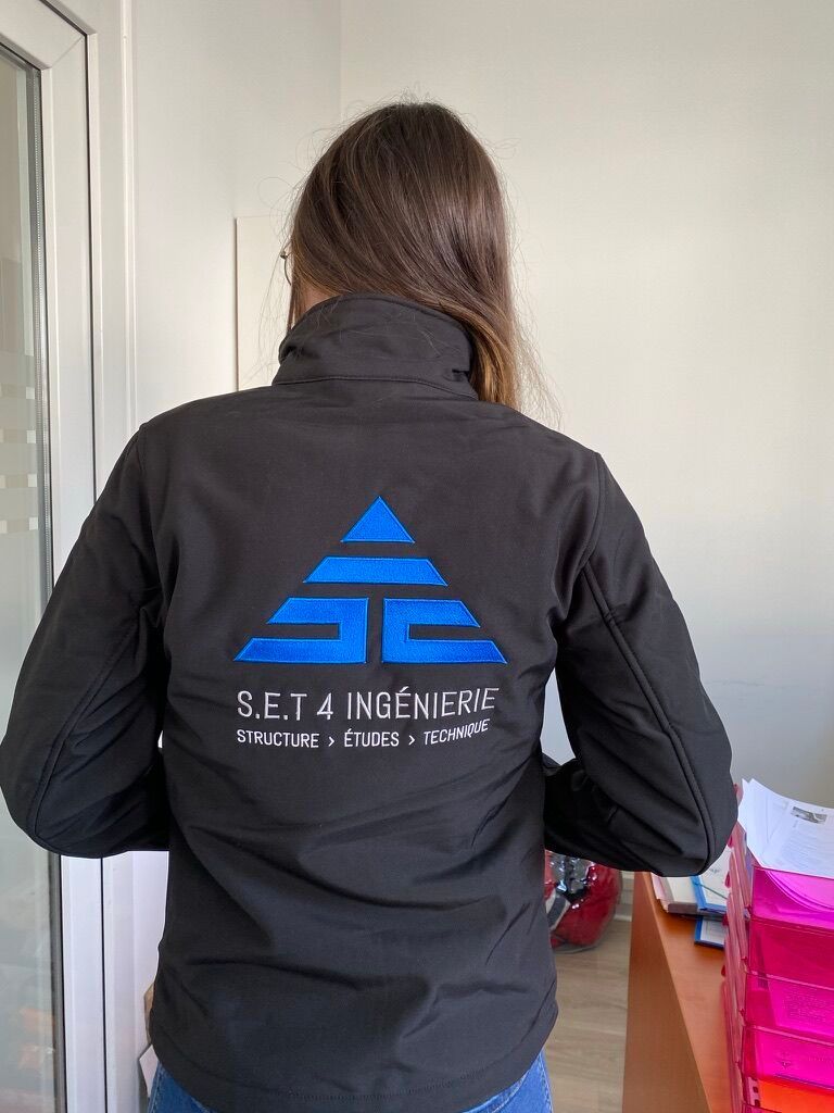Femme portant une veste noire avec un logo triangle bleu ; 
