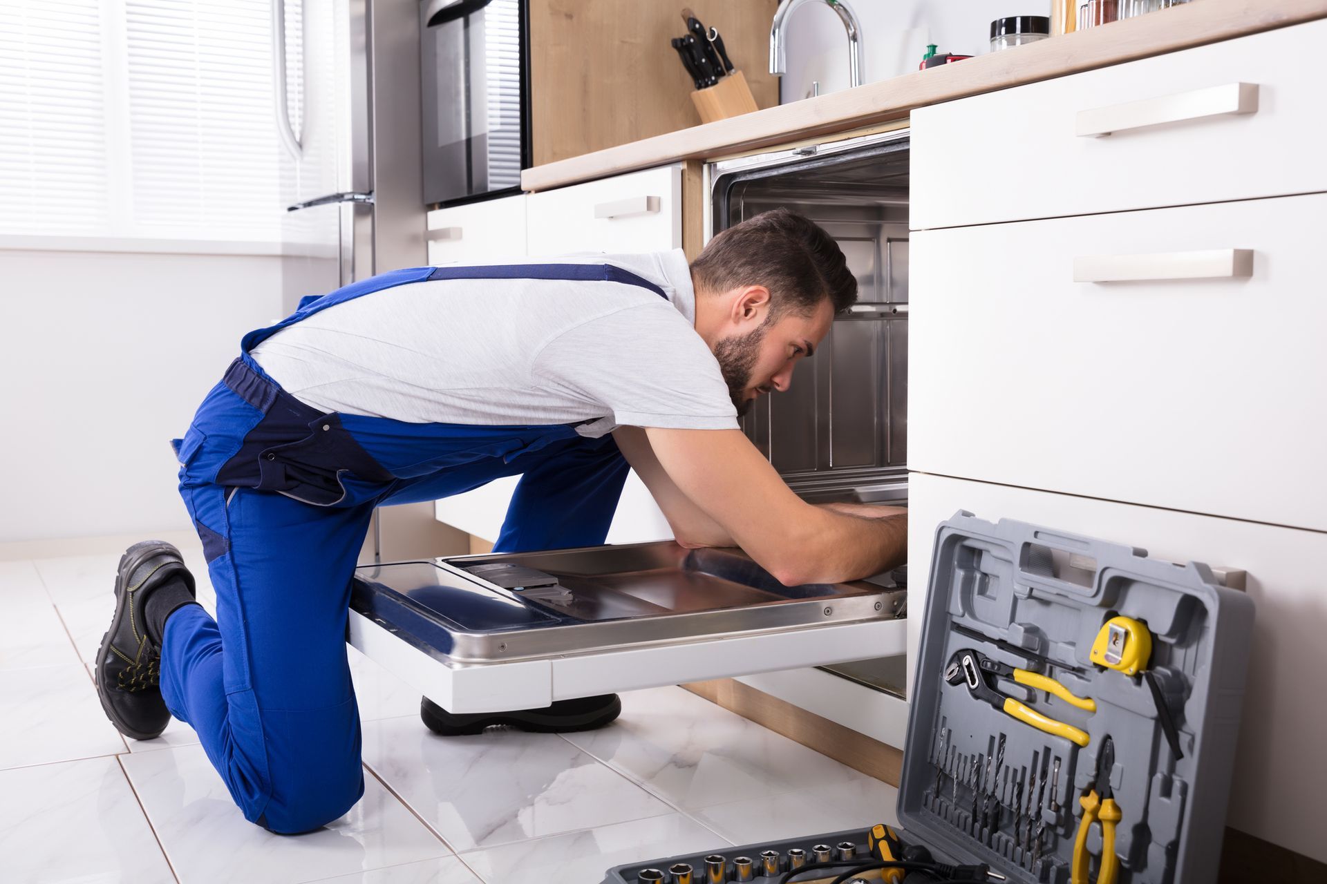 A technician from A Step Above Appliance Repair fixing a dishwasher during an appliance repair servi