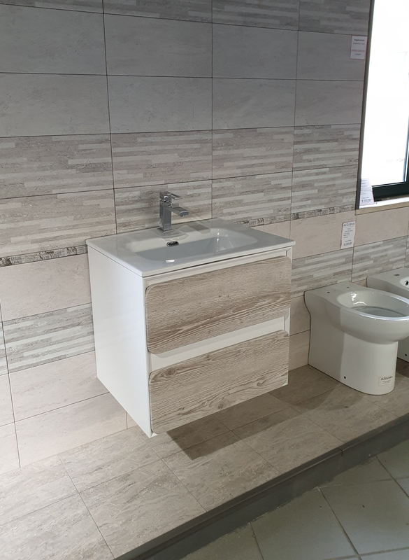 Lavabo moderno con mobiletto bianco, pareti rivestite di piastrelle grigie e WC accanto